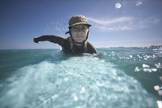 Caucasian woman paddling on surfboard
