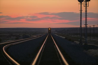 Sunset over train on tracks in rural landscape