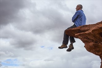Caucasian man sitting on cliff edge
