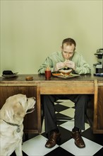 Dog watching Caucasian businessman eat lunch
