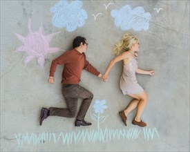 Caucasian couple posing over sidewalk chalk drawing