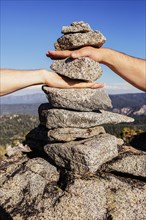 Caucasian couple stacking their hands in rocks