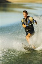 Caucasian man water skiing on lake