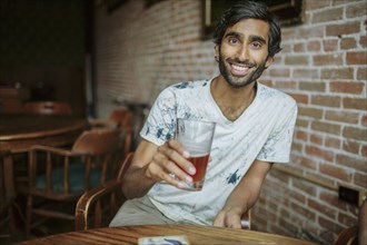 Asian man drinking beer in pub