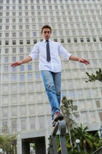 Hispanic businessman balancing on urban railing