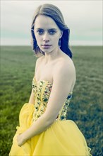 Caucasian teenage girl wearing gown in rural field