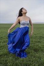 Asian teenage girl wearing gown in rural field