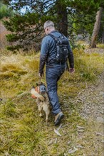 Caucasian man hiking with dog on forest path