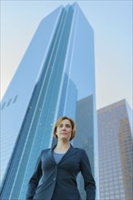 Low angle view of Caucasian businesswoman under high rise buildings