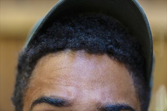 Close up of forehead and baseball cap of mixed race man