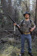 Caucasian hunter holding gun in forest