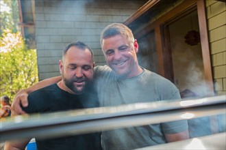 Gay couple grilling food in backyard