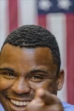Close up of smiling Black man pointing in front of American flag