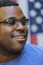 Close up of smiling Black man in front of American flag