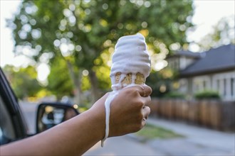 Close up of hand of Chinese girl holding melting ice cream cone