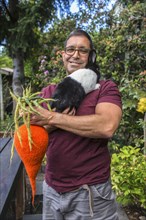 Mixed race man carrying rabbit and knitted carrot