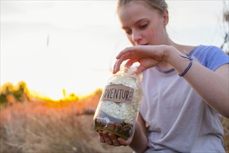Caucasian teenage girl saving money in jar