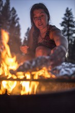 Caucasian woman cooking food over campfire