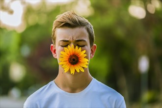 Caucasian teenage boy holding sunflower in mouth
