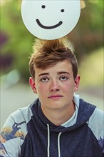 Sad Caucasian teenage boy balancing balloon