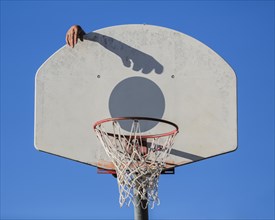 Caucasian man dunking basketball shadow in hoop