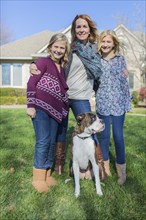 Caucasian mother and daughters smiling with dog