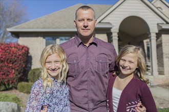 Caucasian father and daughters smiling in yard