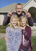 Caucasian father and daughters smiling in yard