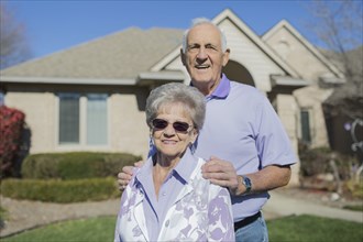 Older Caucasian couple smiling in yard