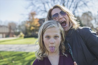 Caucasian mother and daughter making faces outdoors