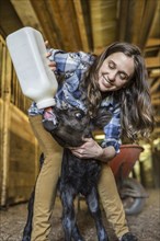 Caucasian farmer feeding calf milk from bottle
