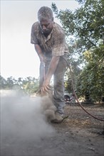 Caucasian man cleaning part with air hose