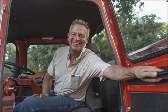 Smiling Caucasian man holding door of tractor