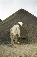 Hispanic man shoveling gravel