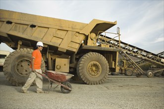 Hispanic man pushing wheelbarrow at gravel plant