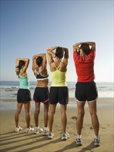 Multi-ethnic female runners stretching at beach
