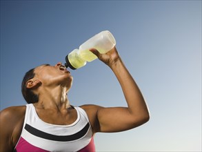 Hispanic woman drinking from squeeze bottle