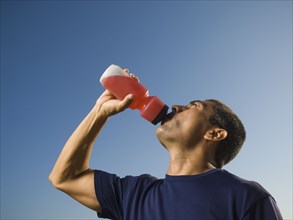 Hispanic man drinking from squeeze bottle