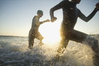 Multi-ethnic swimmers running in surf