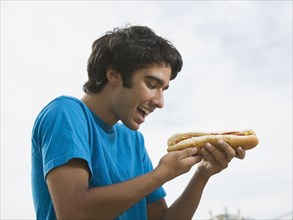 Mixed Race teenaged boy eating hot dog