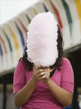 Mixed Race girl holding cotton candy in front of face