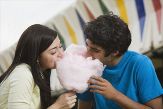 Multi-ethnic teenaged couple eating cotton candy