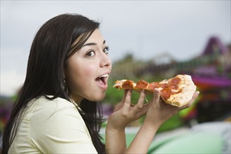 Mixed Race teenaged girl eating pizza