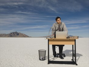 Hispanic businessman at desk on salt flats