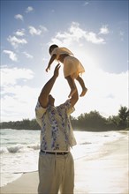 Pacific Islander father playing with son at beach