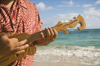 Pacific Islander man playing instrument at beach