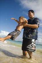 Pacific Islander father and son playing at beach