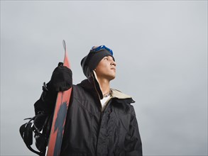 Mixed race teenager standing with snowboard