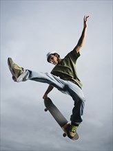Mixed race teenager in mid-air on skateboard