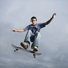 Mixed race teenager in mid-air on skateboard